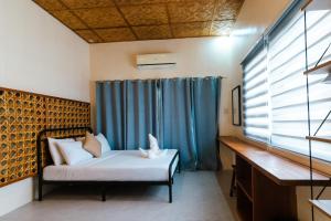a bedroom with a bed and a blue curtain at The Shack Hideaway by Mayumi Resorts in Mabini