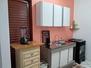 a kitchen with white cabinets and a counter top at kitnet Ceu in Campo Grande