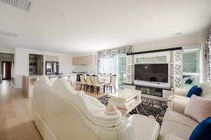 a living room with white furniture and a kitchen at Neat and tidy house in Cranbourne