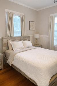 a white bedroom with a large bed with white sheets at Relaxing Poolside Condo in Savannah +28 photos