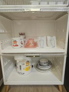 a white refrigerator filled with dishes and cups and pans at Khiri&Kiwi homestay in Ban Mae Rim Nua