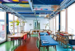 a dining room with tables and chairs and windows at Hotel KAZENOIRO in Iioka