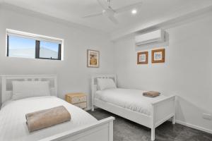 a white bedroom with two beds and a window at Williamstown Townhouse in Williamstown