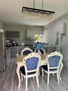 a kitchen with a wooden table with chairs and a dining room at Paiyawadee House khaoyai in Ban Hua Phrong