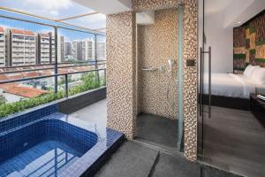 a bathroom with a shower and a tub with a bed at A Hotel Dickson in Singapore