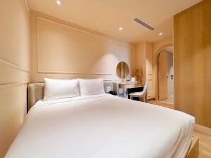 a bedroom with a large white bed and a desk at Peace Home Boutique Hotel in Phan Thiet