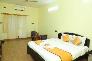 a bedroom with a large bed with orange and white pillows at Hotel Priso in Kālapettai +46 photos