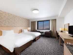 a hotel room with two beds and a desk at Mercure Miyagi Zao Resort & Spa in Zao