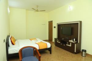 a hotel room with a bed and a television at Hotel Priso in Kālapettai