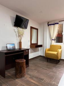 a living room with a desk and a yellow chair at Hotel & Suites Cerro Roj0 in Tlatlauquitepec