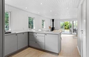 a white kitchen with white cabinets and windows at Nice Home In Farsø With House A Panoramic View in Farsø +20 photos