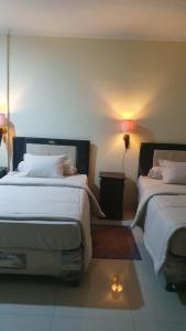 a bedroom with two beds and a lamp at Deva'sya Room Rent Nusa Dua in Nusa Dua