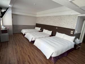 two beds in a room with white sheets at Long Siang Hotel in Kaohsiung