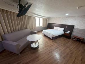 a bedroom with a bed and a couch and a table at Long Siang Hotel in Kaohsiung