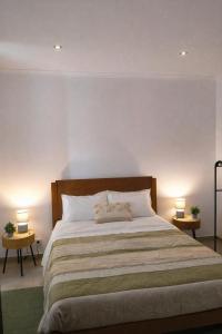 a bedroom with a large bed with two lamps at Alojamento dos cagarros in São Sebastião