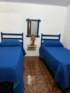 two beds in a room with blue sheets and a window at Picaflor in Barra del Chuy