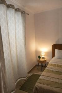 a bedroom with a bed and a table with a lamp at Alojamento dos cagarros in São Sebastião