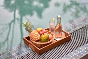 a tray with a basket of fruit and a bottle of drink at Rain Drops Wellness Villa Deniyaya, Sinharaja in Deniyaya