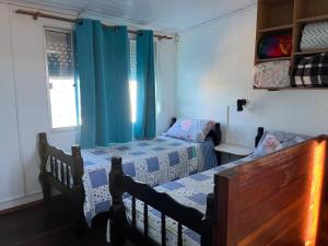 two beds in a bedroom with blue curtains at Apartamento in Barra del Chuy