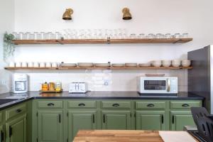 a kitchen with green cabinets and a microwave at Spacious Haven near Busch ABODEbucks in Soulard +42 photos