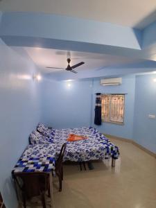 a blue room with a table and a ceiling fan at Bhakta Bhawan in mayapur