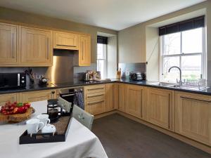 a kitchen with wooden cabinets and a table with fruit on it at Dunvegan Castle Gardens Cottage in Dunvegan