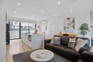 a living room with a brown couch and a kitchen at Williamstown Townhouse in Williamstown