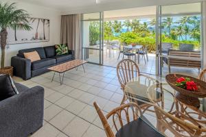 a living room with a couch and a table and chairs at Whitsunday Apartments on Hamilton Island by HIHA in Hamilton Island