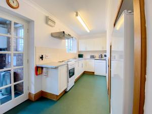 a kitchen with white cabinets and a green floor at Sweet Coppin in Ledbury