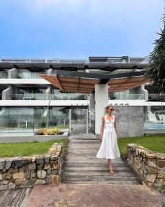 a woman in a white dress standing on a wooden walkway at 71 Hastings - Beachfront in Noosa Heads