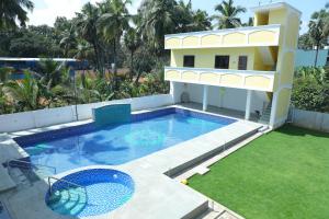 a house with a swimming pool next to a building at Hotel Priso in Kālapettai