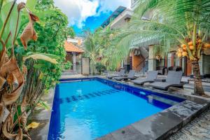 a swimming pool in front of a house with palm trees at Wana Kubu Suite and Dormitory in Ngurah Rai International Airport