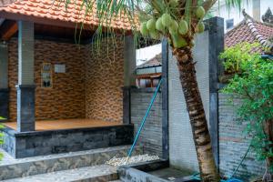 a palm tree in front of a house with a hose at Wana Kubu Suite and Dormitory in Ngurah Rai International Airport