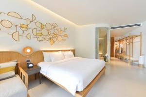 a bedroom with a large white bed with music notes on the wall at SYLVAN Koh Chang in Ko Chang