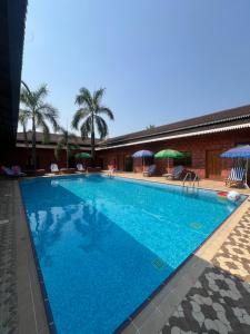 a large blue swimming pool with chairs and umbrellas at Benzy Palace Resort, Murdeshwar in Māvalli