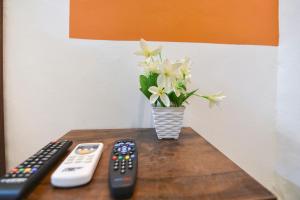 two remote controls and a vase of flowers on a table at HOTEL O THE G STAY in Chinchwad +25 photos
