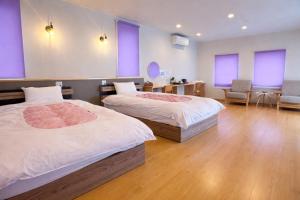 two beds in a room with purple windows at 舒爽旅馆 in Fuefuki