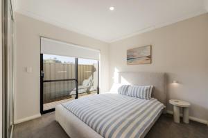 a bedroom with a bed and a balcony at 9 by the Beach in Rockingham