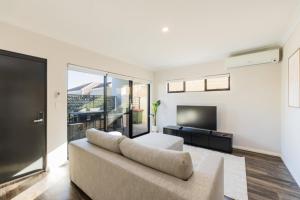 a living room with a couch and a flat screen tv at 9 by the Beach in Rockingham