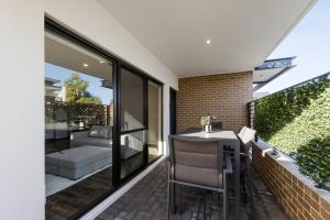 a patio with a table and chairs on a balcony at 9 by the Beach in Rockingham