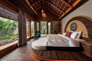 a bedroom with a large bed in a room with windows at Lamia Bamboo Retreat Ninh Binh in Ninh Binh