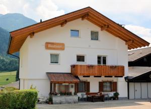 ein großes weißes Haus mit einem Holzbalkon in der Unterkunft Privatpension Bergkristall in Sankt Martin in Passeier