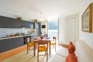 a kitchen and living room with a table and a couch at Villa L'Approdo in Porlezza