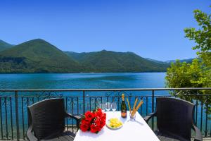 a table with flowers and a bottle of wine on a balcony at Villa L'Approdo in Porlezza