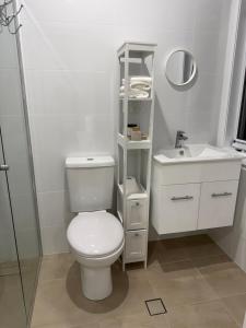 a white bathroom with a toilet and a sink at Cosy Granny flat in Epping in Epping +4 photos