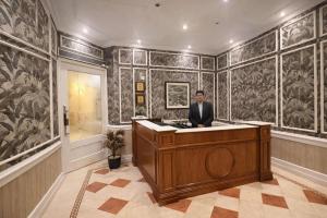 a man in a suit sitting at a desk in a room with wallpaper at Hotel Bright in New Delhi