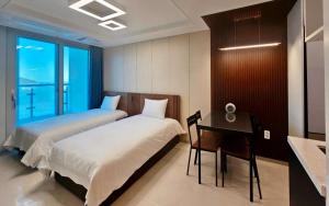a bedroom with two beds and a desk and a sink at Hyoi Stay Busan Songdo in Damyang