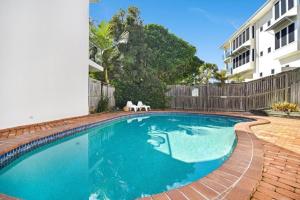 a swimming pool with two white chairs next to a building at Suntan at Sunshine in Sunshine Beach