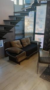 a black couch in a living room with windows at Кичук Париж in Plovdiv