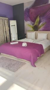 a large bed with a purple blanket on it at Кичук Париж in Plovdiv